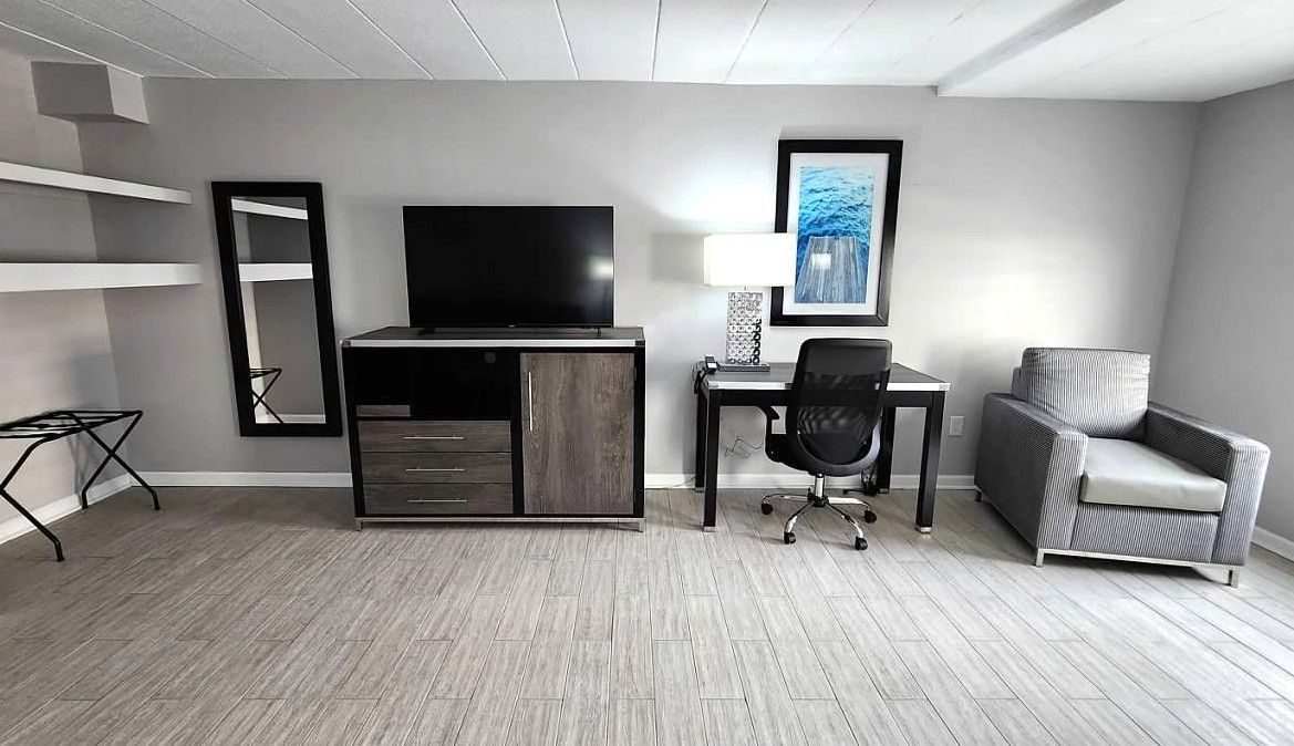 A hotel room with a desk , chair and television.