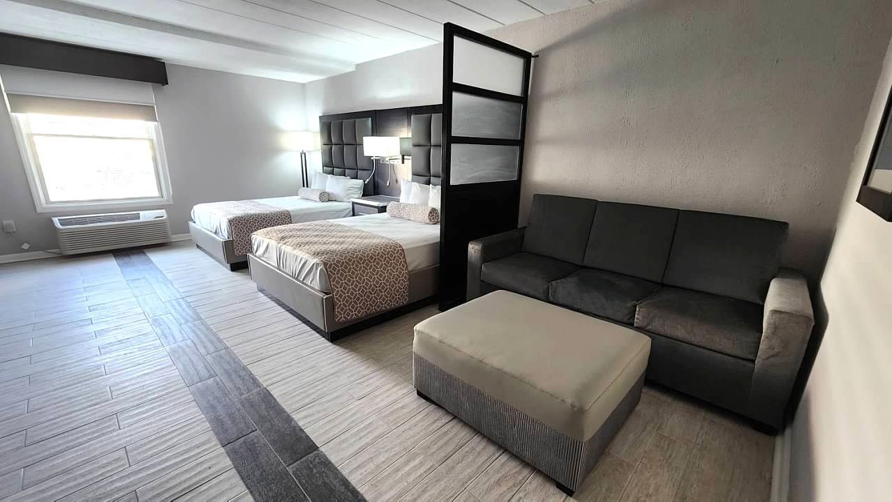 A hotel room with two beds and a couch.