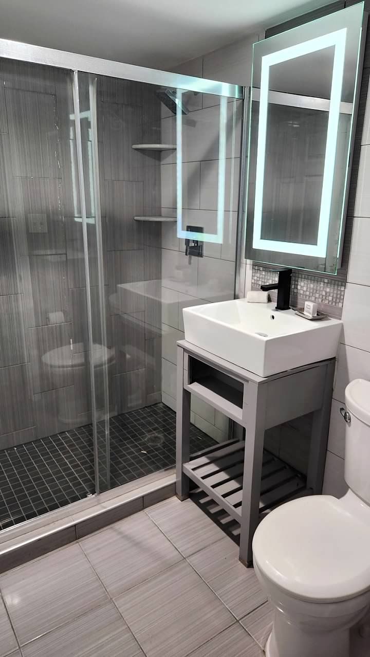A bathroom with a sink , toilet , shower and mirror.