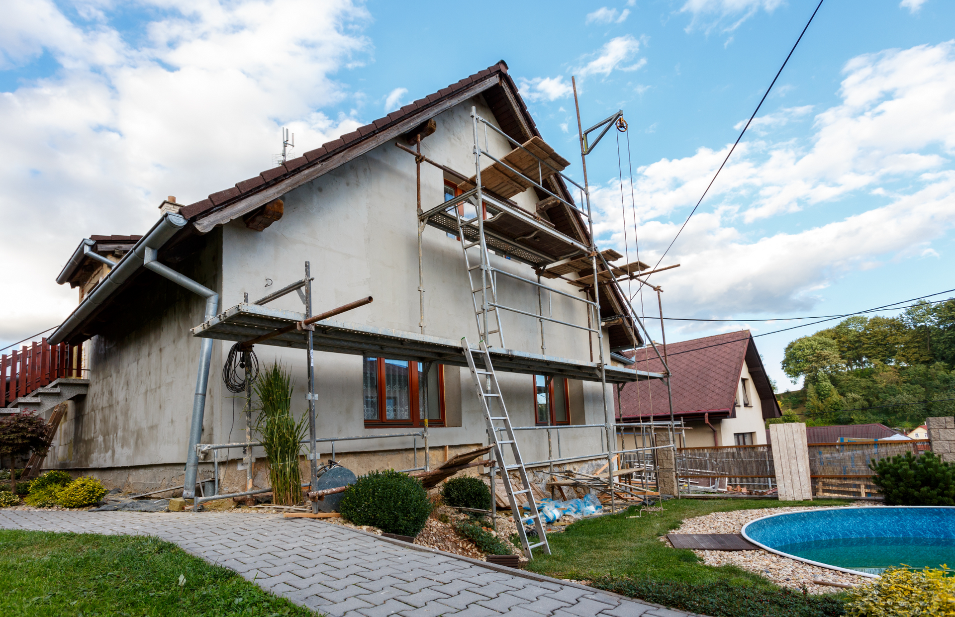 A house is being remodeled with scaffolding and a pool in the backyard.