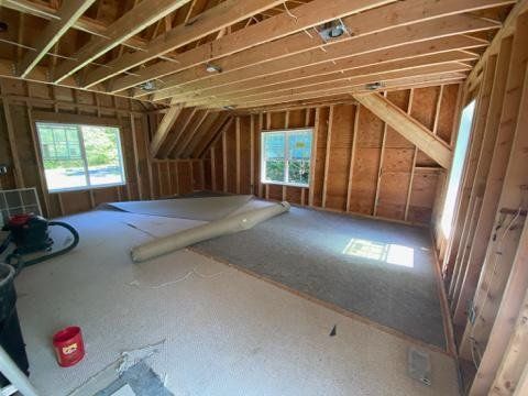 A room with a vacuum cleaner and a roll of carpet on the floor.