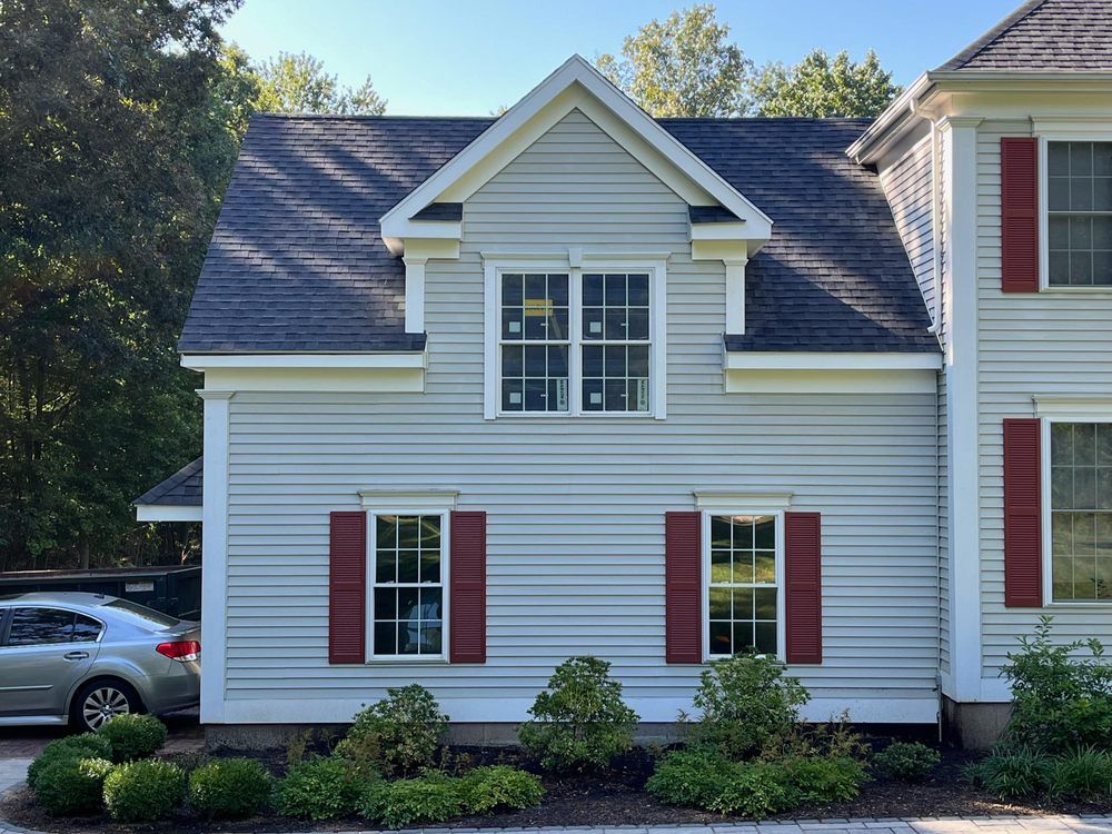 A white house with red shutters and a car parked in front of it