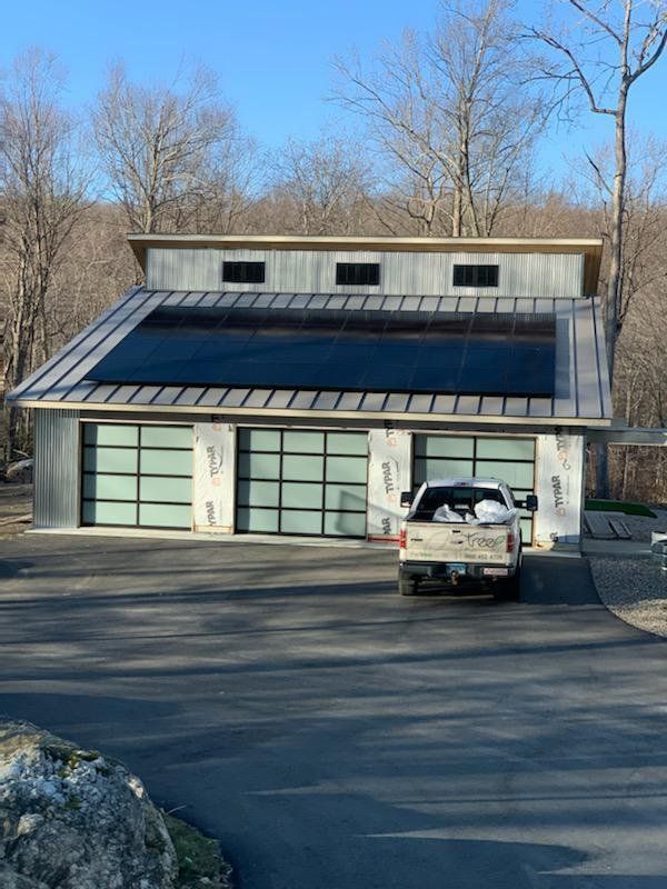 A truck is parked in front of a house with solar panels on the roof.