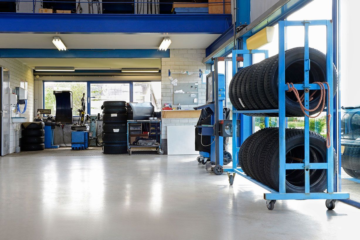 Auto shop interior with blue tire racks, tools, and a polished floor