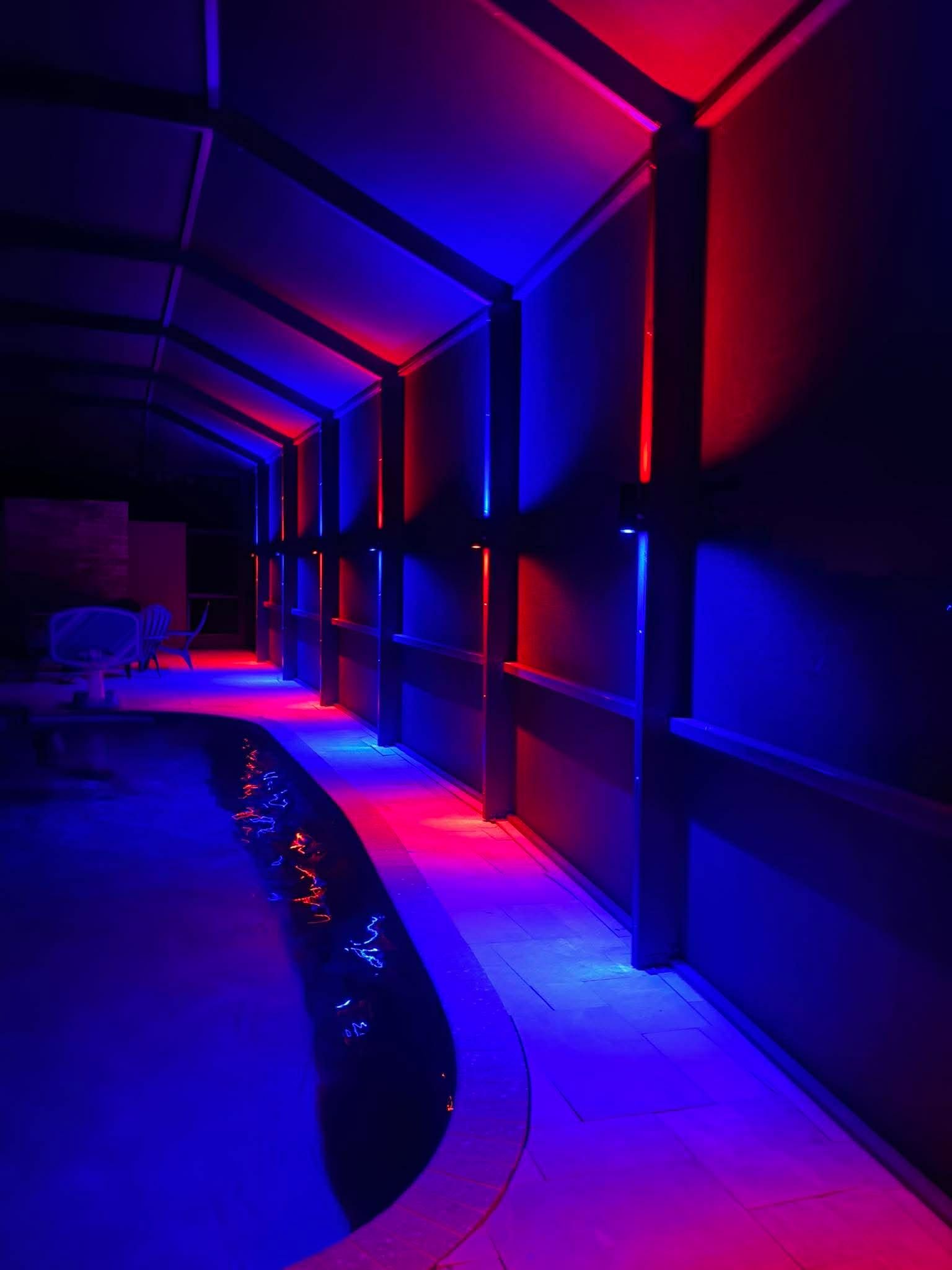 Neon-lit corridor with purple and blue lighting beside a curved water feature