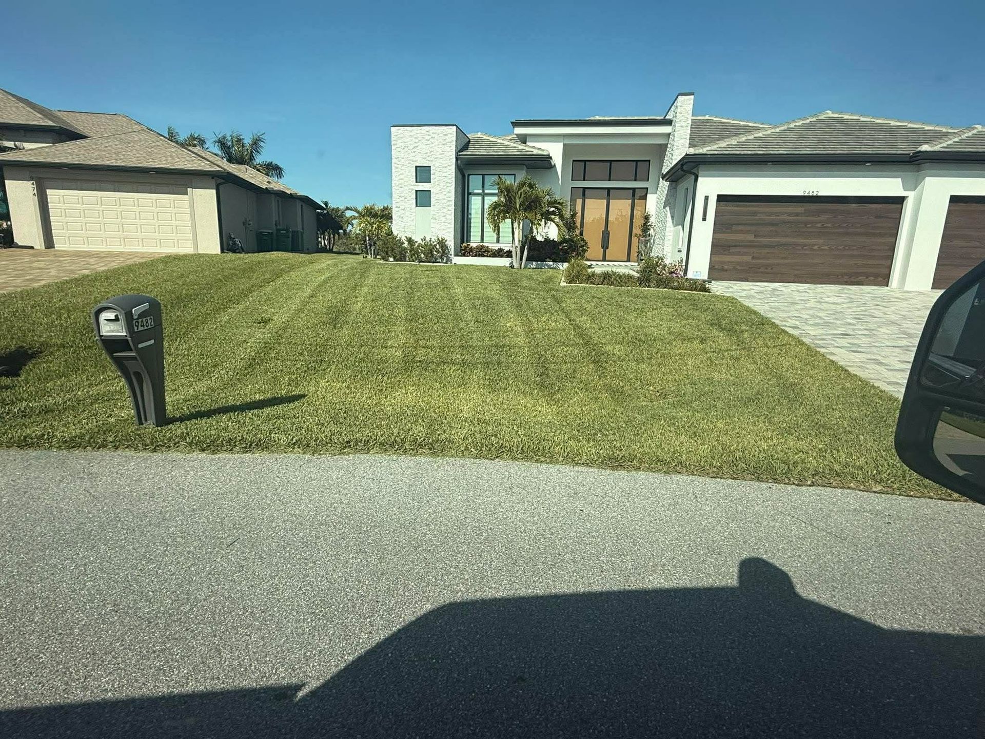 Suburban house with a manicured front lawn, garage, and driveway seen from the street
