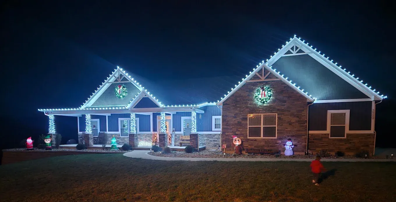 House with blue Christmas lights and holiday decorations at night.