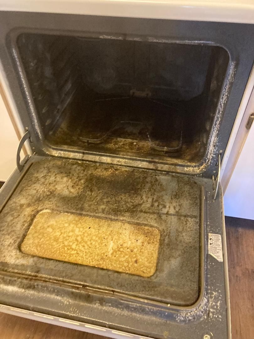 Dirty oven with burnt residue and a baking dish inside.
