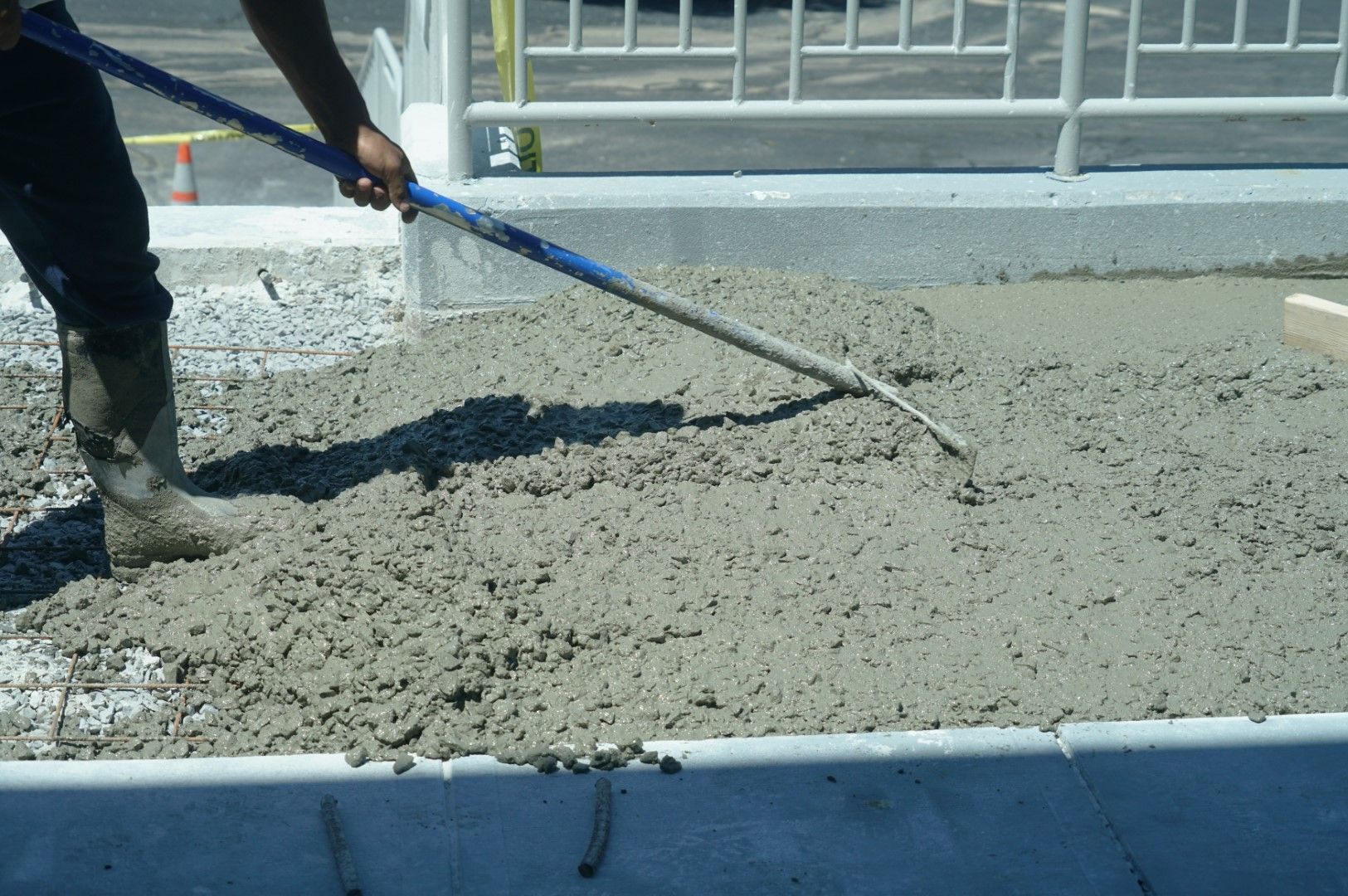 A man is spreading concrete with a rake.