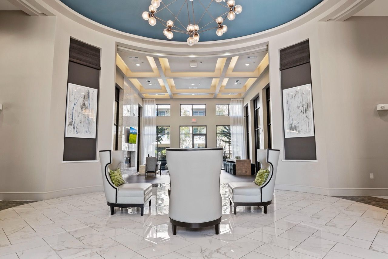Bright apartment lobby with circular white seating, marble floors, and a modern chandelier.