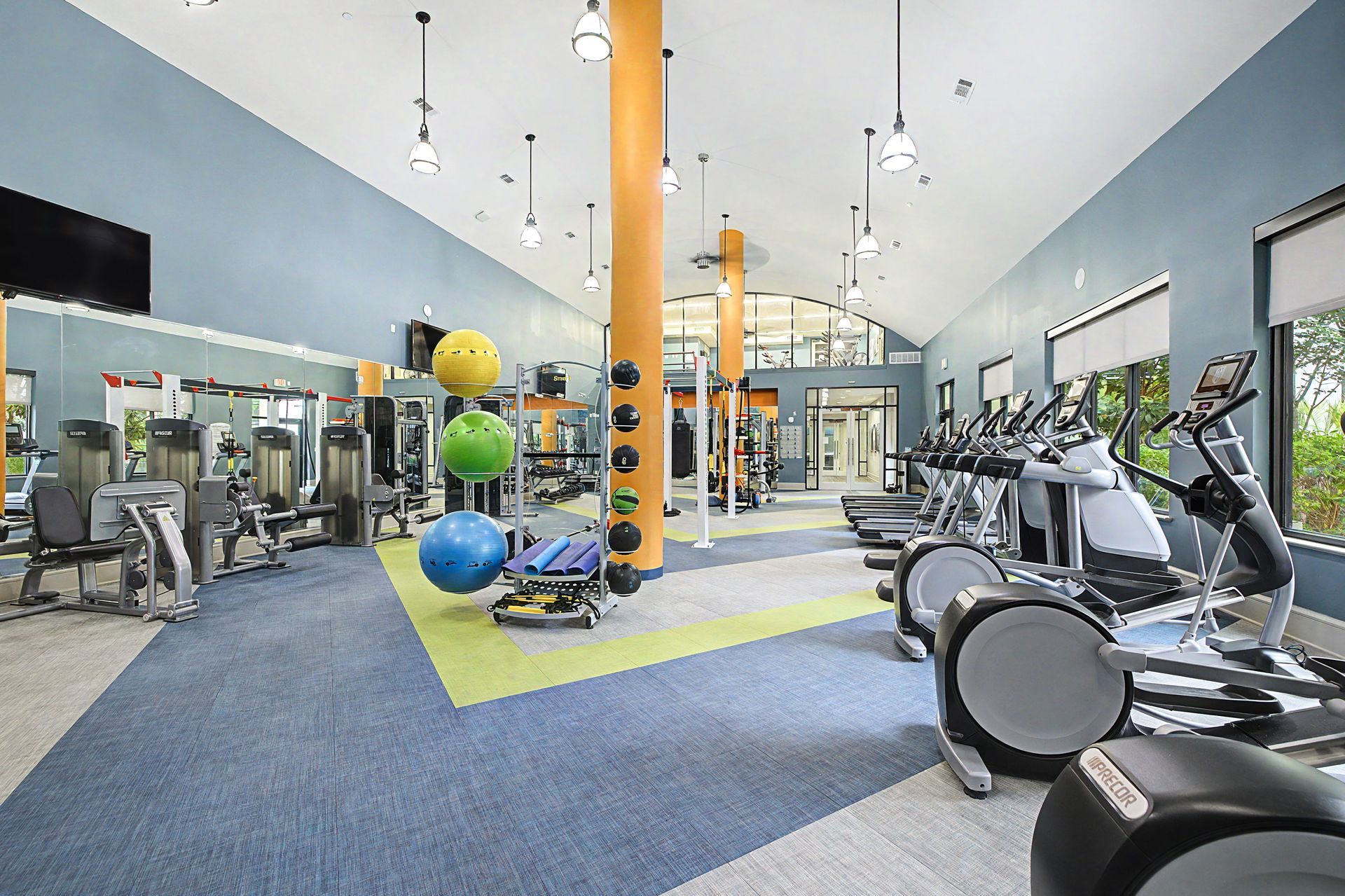 Bright modern gym with treadmills, exercise bikes, mirrors, and colorful stability balls at Olympus at Memorial, offering townhomes for rent in the Memorial area of Houston, TX.