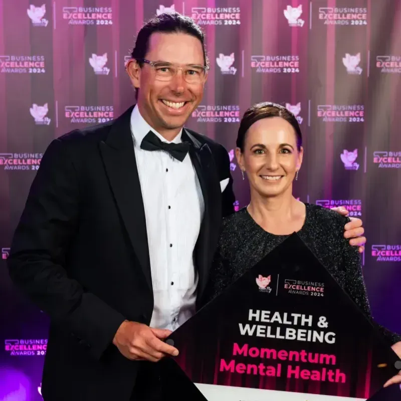 Chris Black and a woman are holding a health and wellbeing business excellence award for momentum me