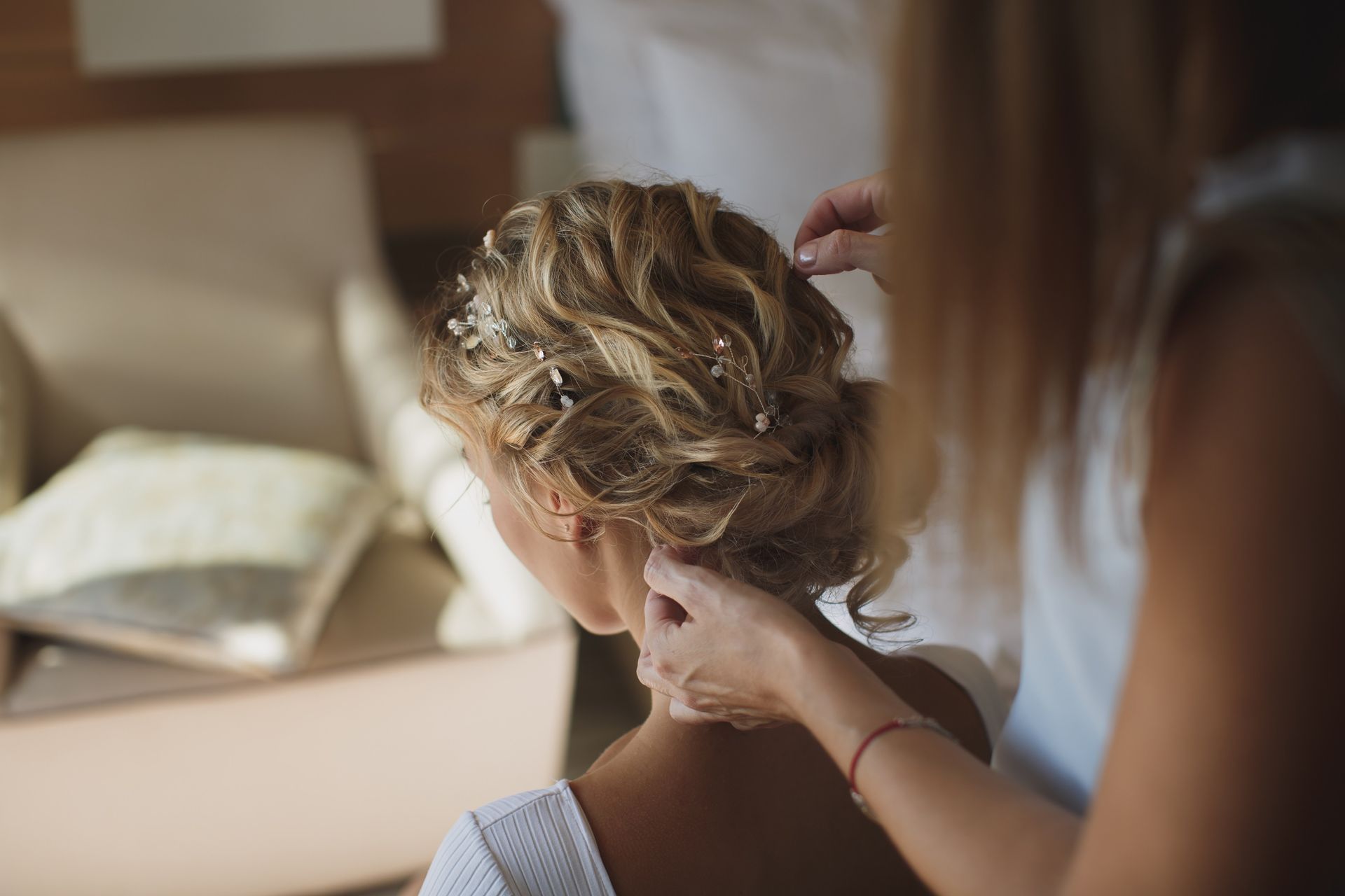 Person styling another's hair in a softly lit bedroom