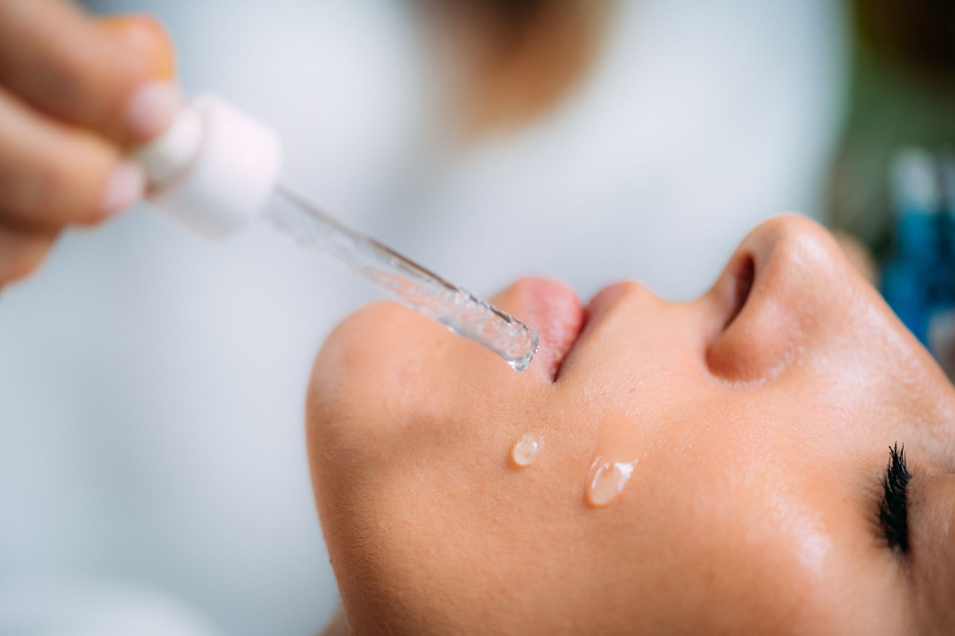Dropper applying serum to a person’s face during a skincare treatment
