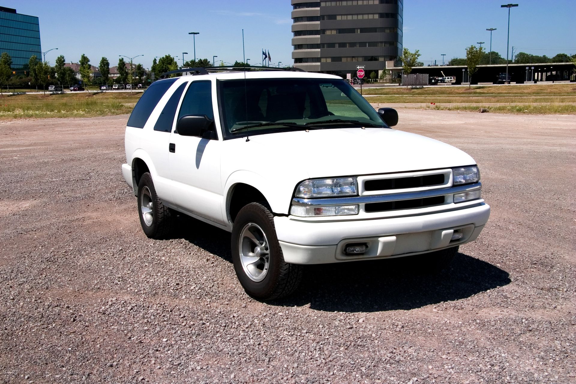 A white suv is parked in a gravel lot