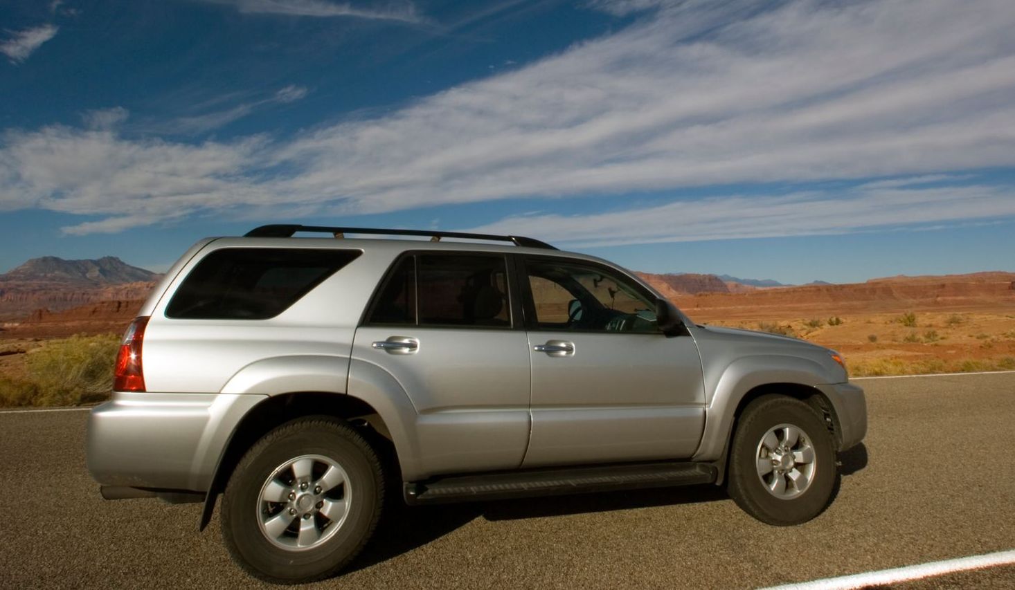 A silver suv is parked on the side of the road