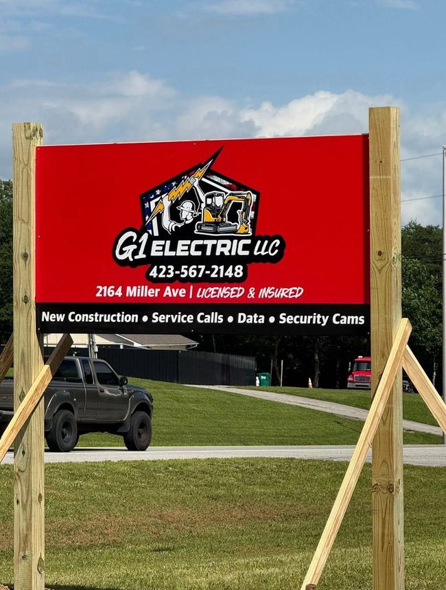 Red G1 Electric LLC roadside sign with contact information on a grassy roadside