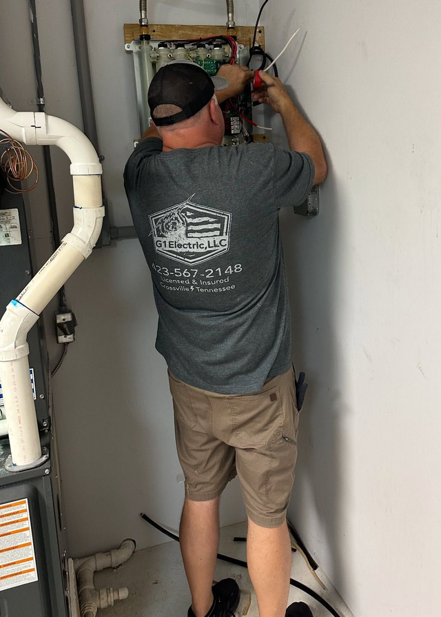 Technician working on wall-mounted pipes and valves in a utility closet