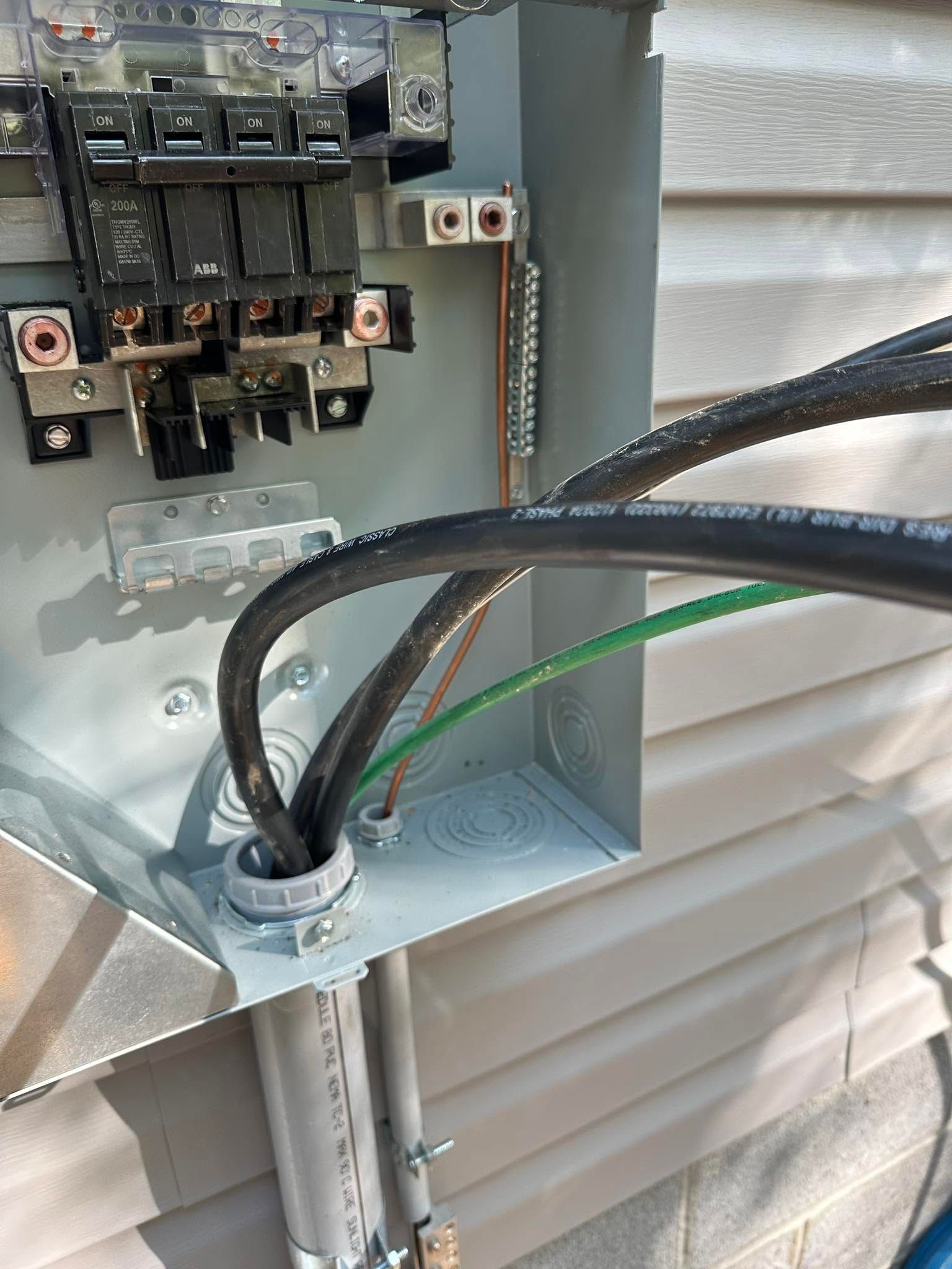 Open electrical breaker panel with wiring and conduit on a building exterior wall