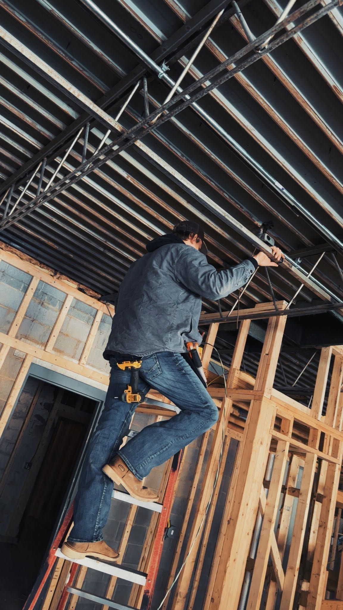 Worker climbing a ladder inside an unfinished wooden building frame