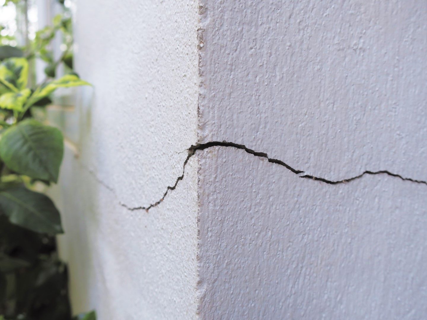 White wall with a dark crack running along its corner.