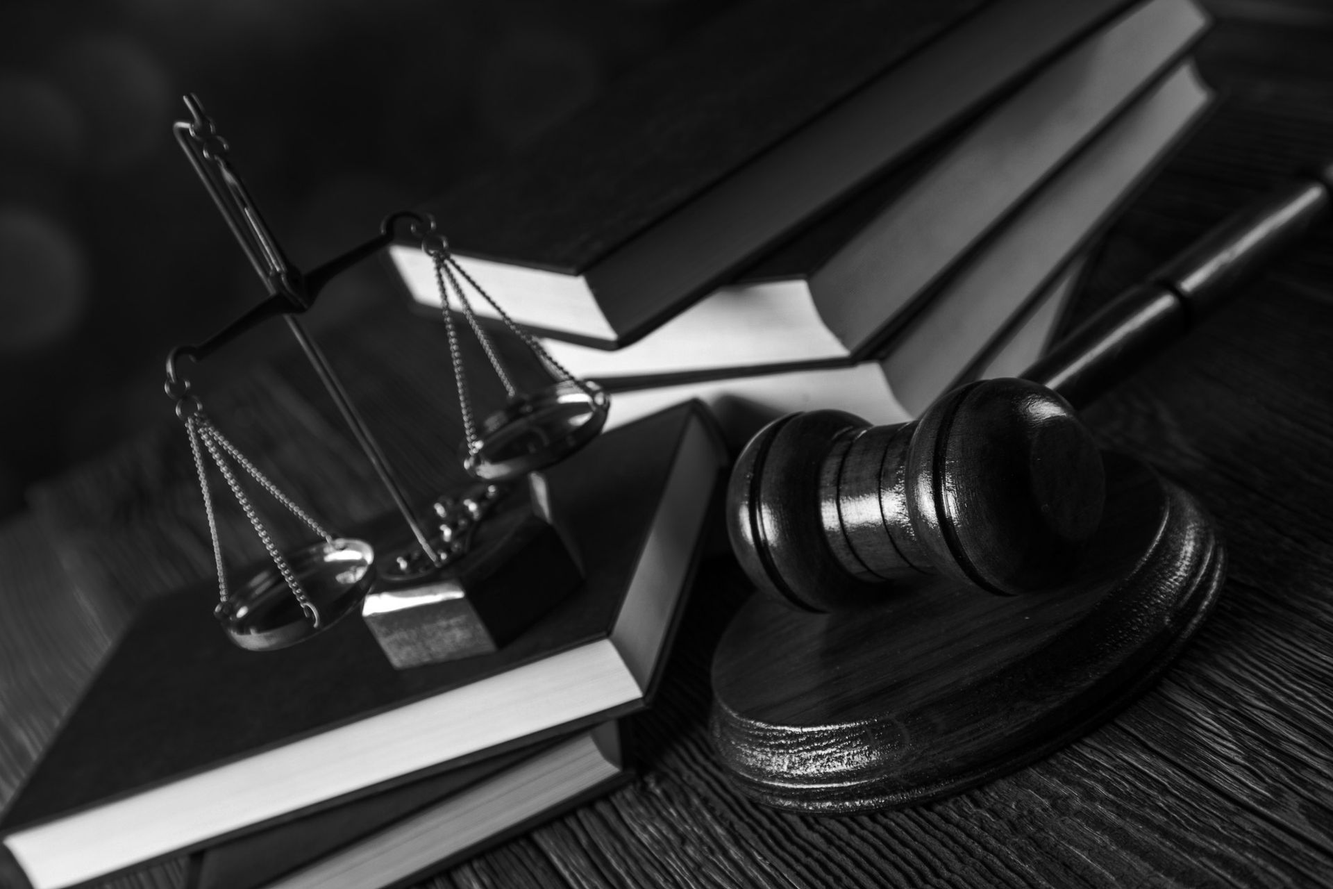 Scales of justice, gavel, and books on a wooden surface, black and white. Scales of justice, gavel, and books on a wooden surface, black and white.