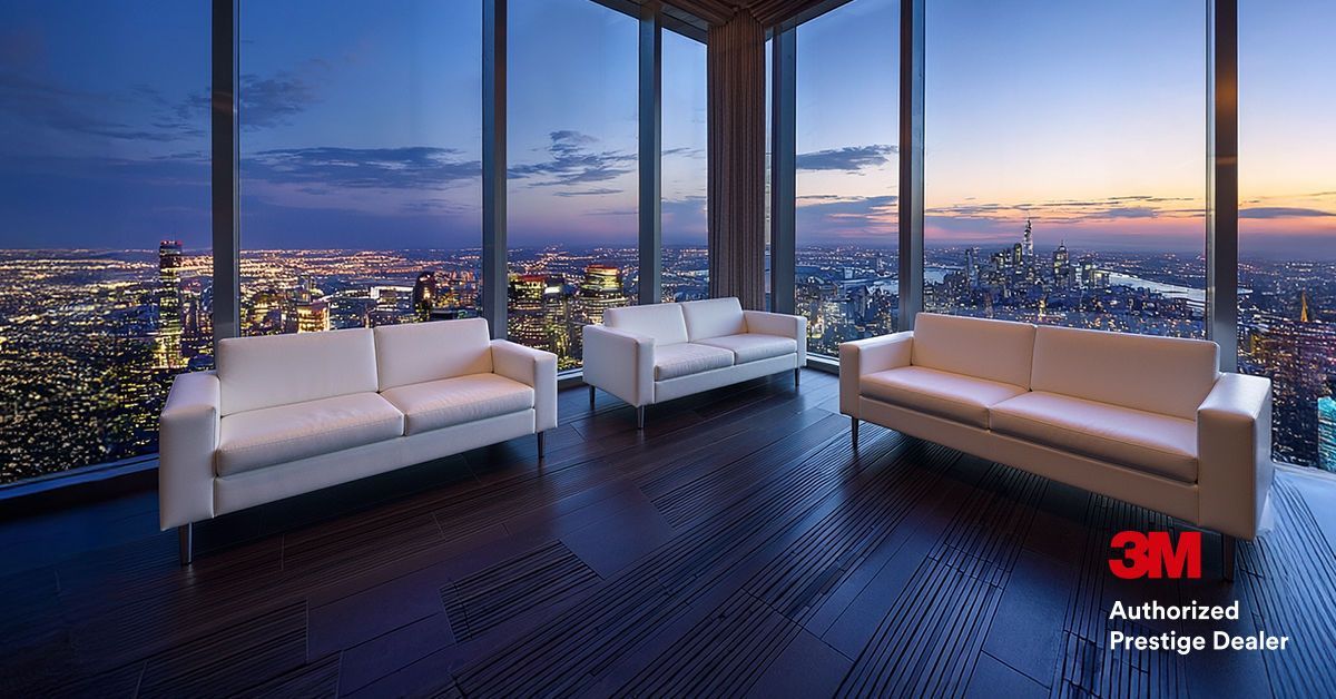 City skyline viewed through a modern window, framed by dark architectural elements; daytime.