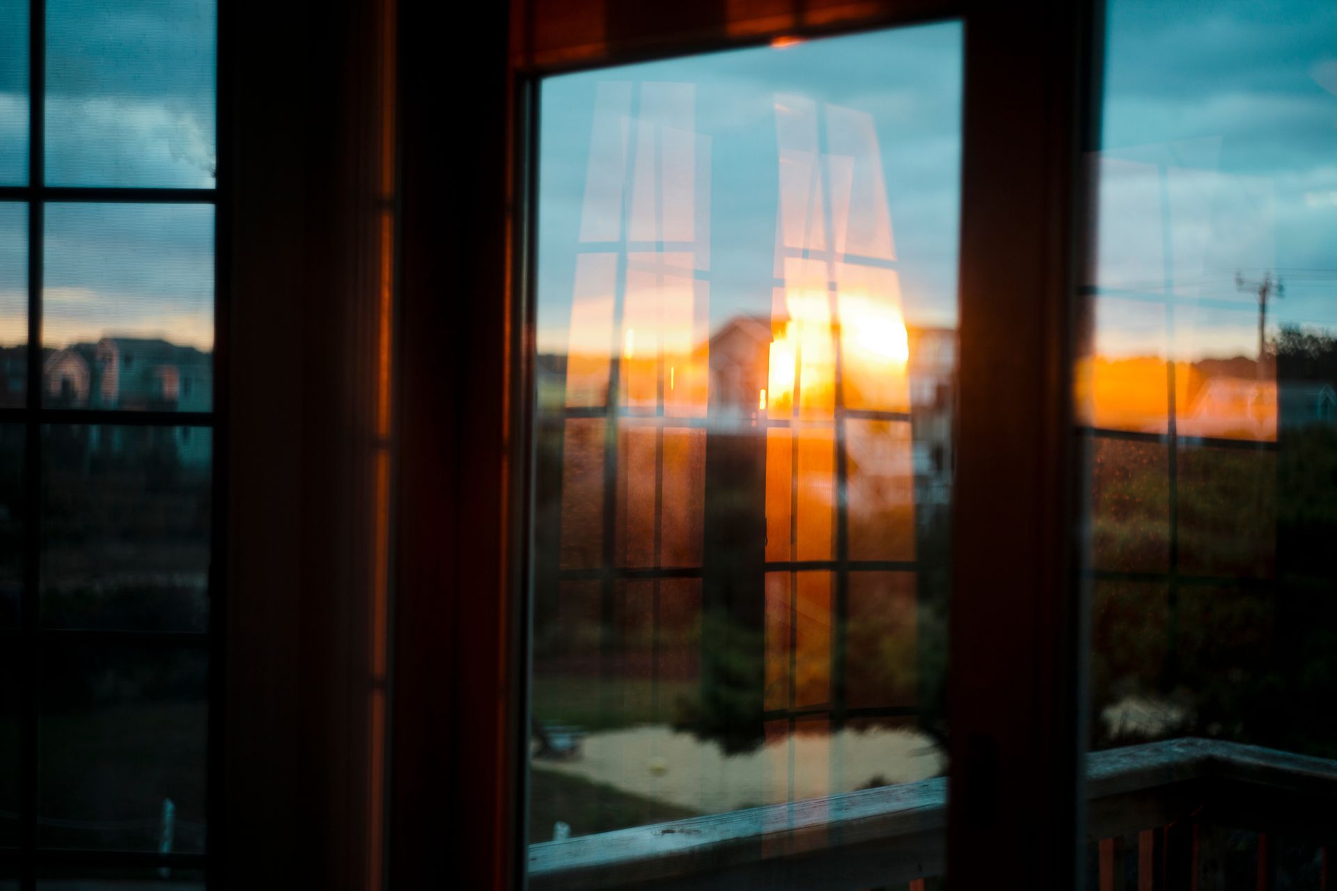 Sunrise reflected on home windows showcasing residential window tinting for energy efficiency.