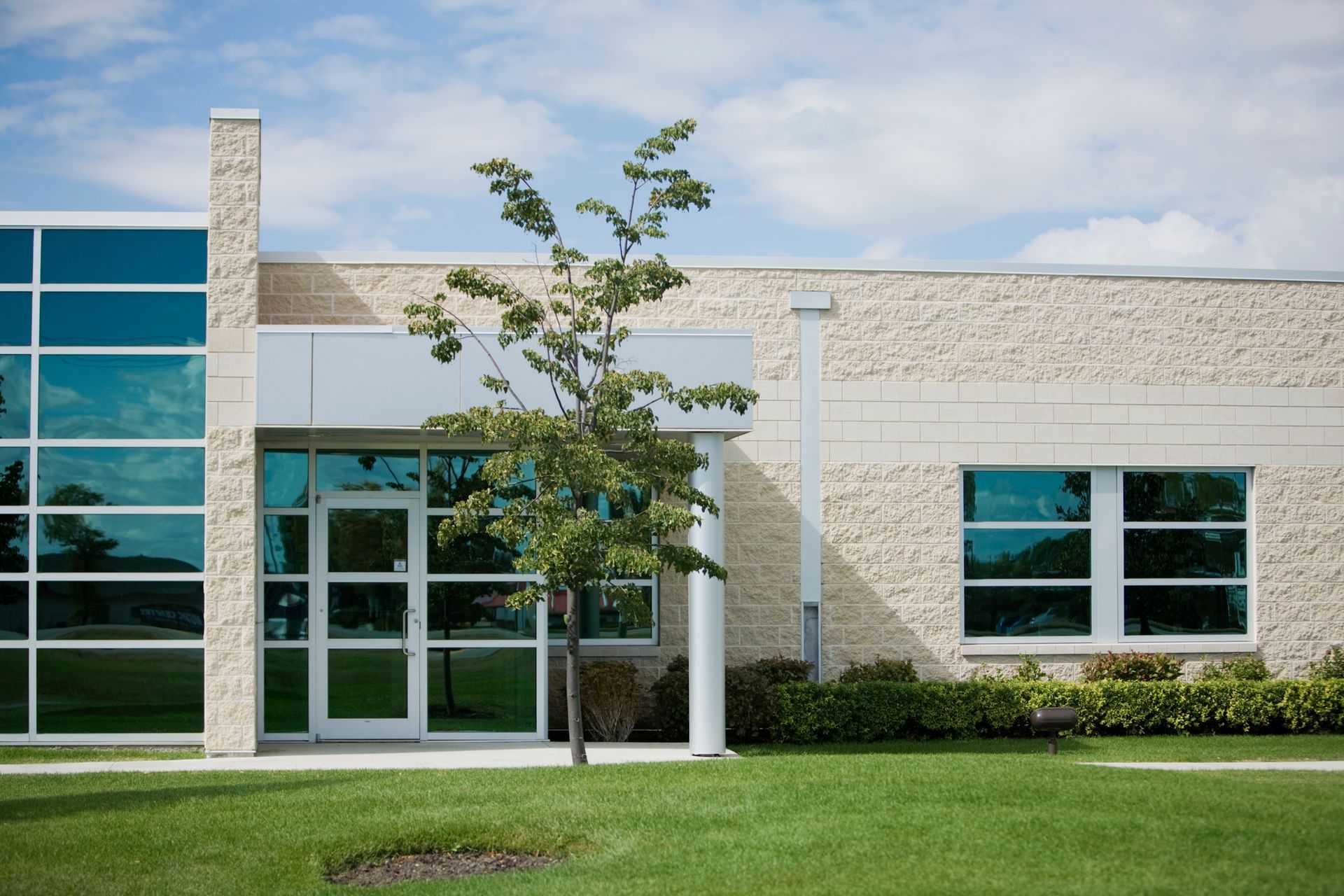 A building with large windows and a tree in front, representing commercial windows glare control