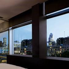 City skyline viewed through a modern window, framed by dark architectural elements; daytime.