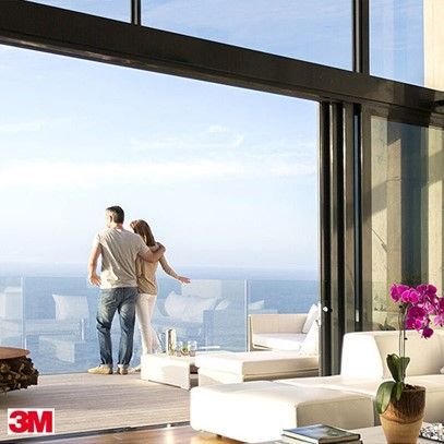 Couple gazing at ocean view from a modern, sunlit home.