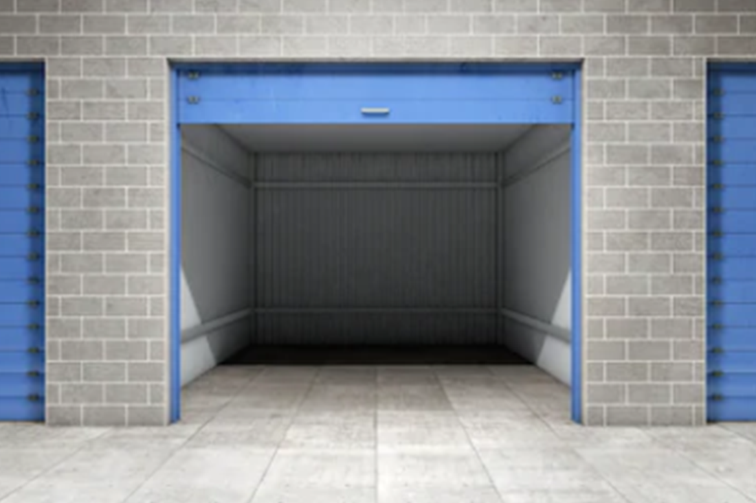 Empty blue storage unit with open door, surrounded by brick walls.