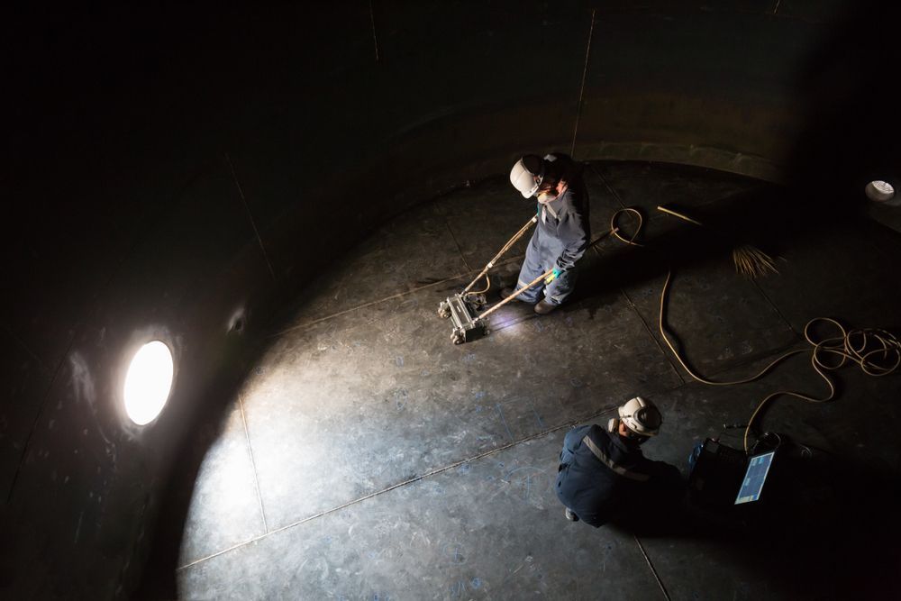 Two Workers Inside a Dark Tank, Using Equipment — Phoenix Protective & Marine Coating Specialists in Atherton Tablelands, QLD