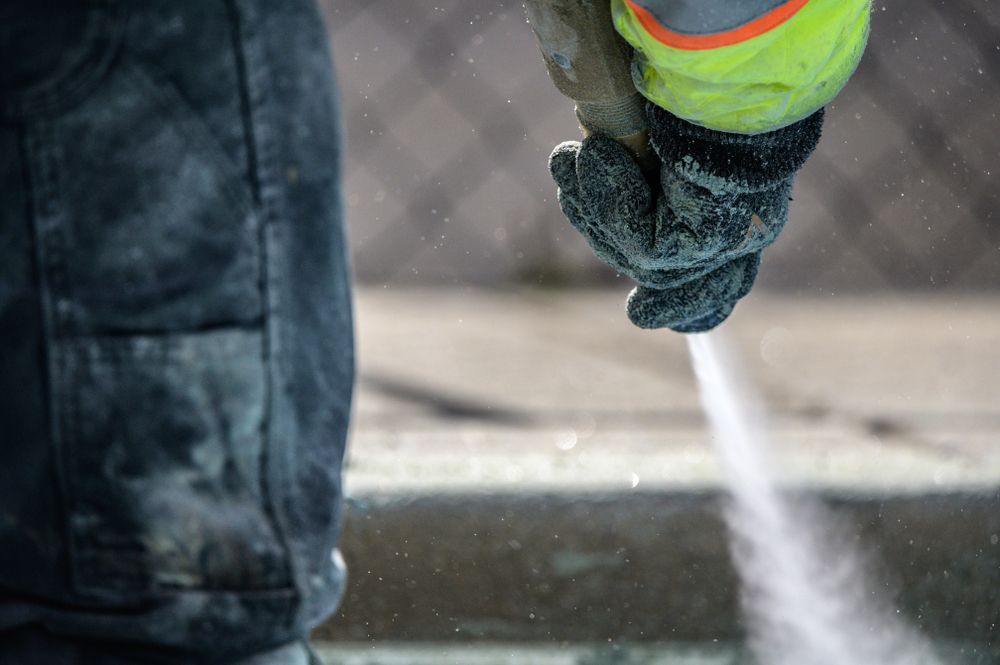 Person in Work Clothes Using a Hose — Phoenix Protective & Marine Coating Specialists in Woree, QLD