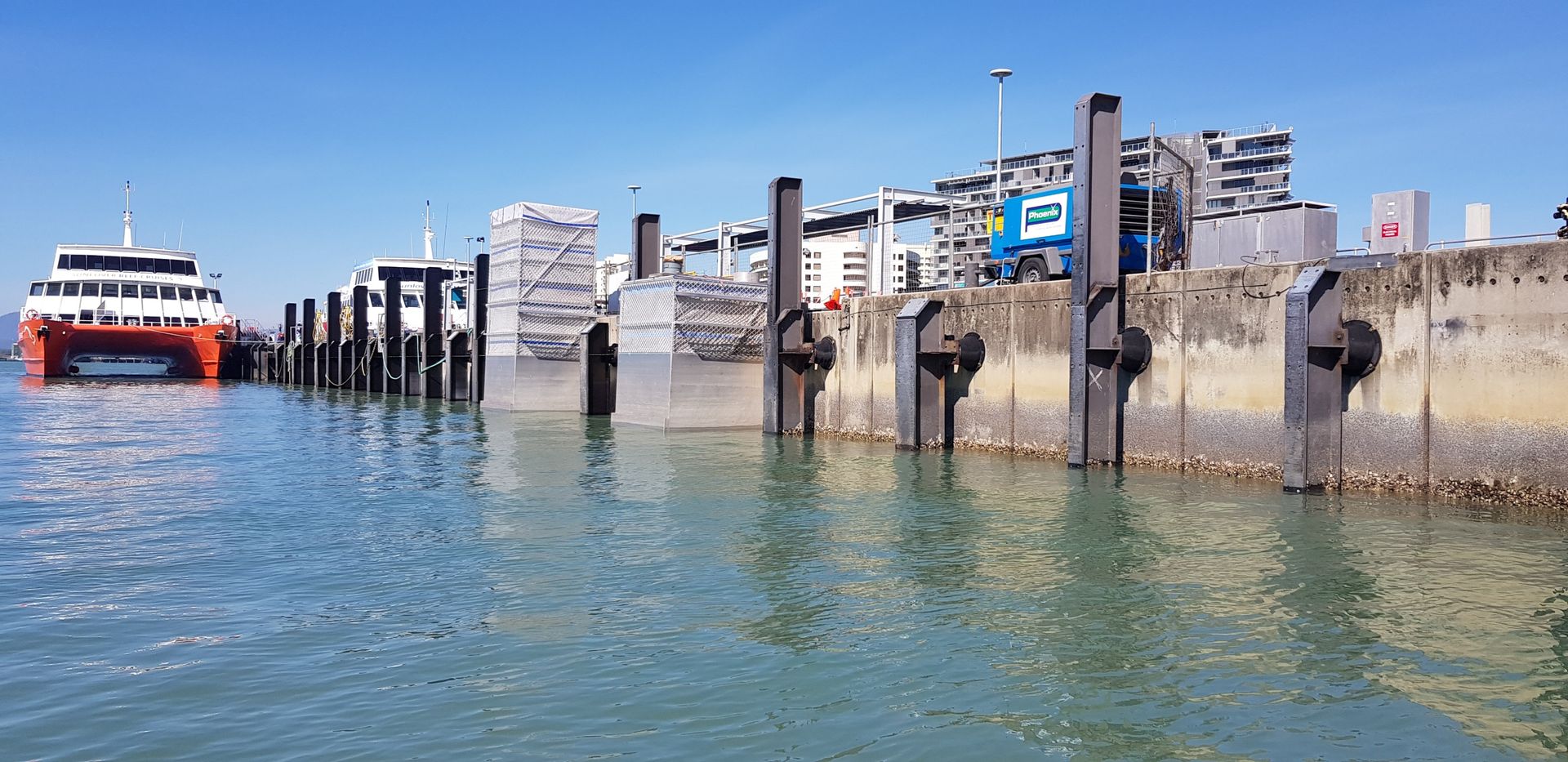 Ferry docked beside weathered concrete pier on calm blue water under a clear sky