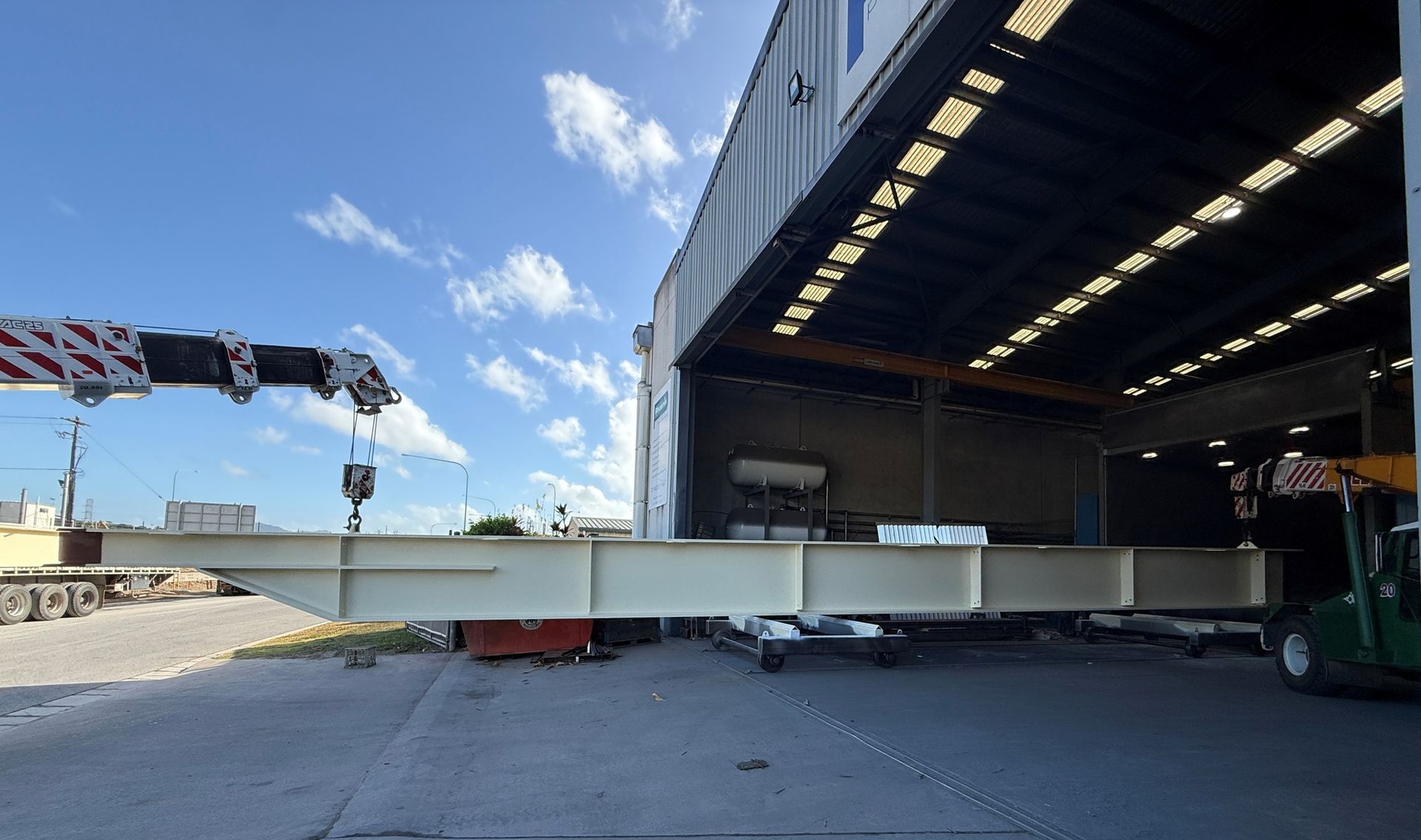 A Long, Pale Steel Beam Being Lifted Into a Building — Phoenix Protective & Marine Coating Specialists in Woree, QLD