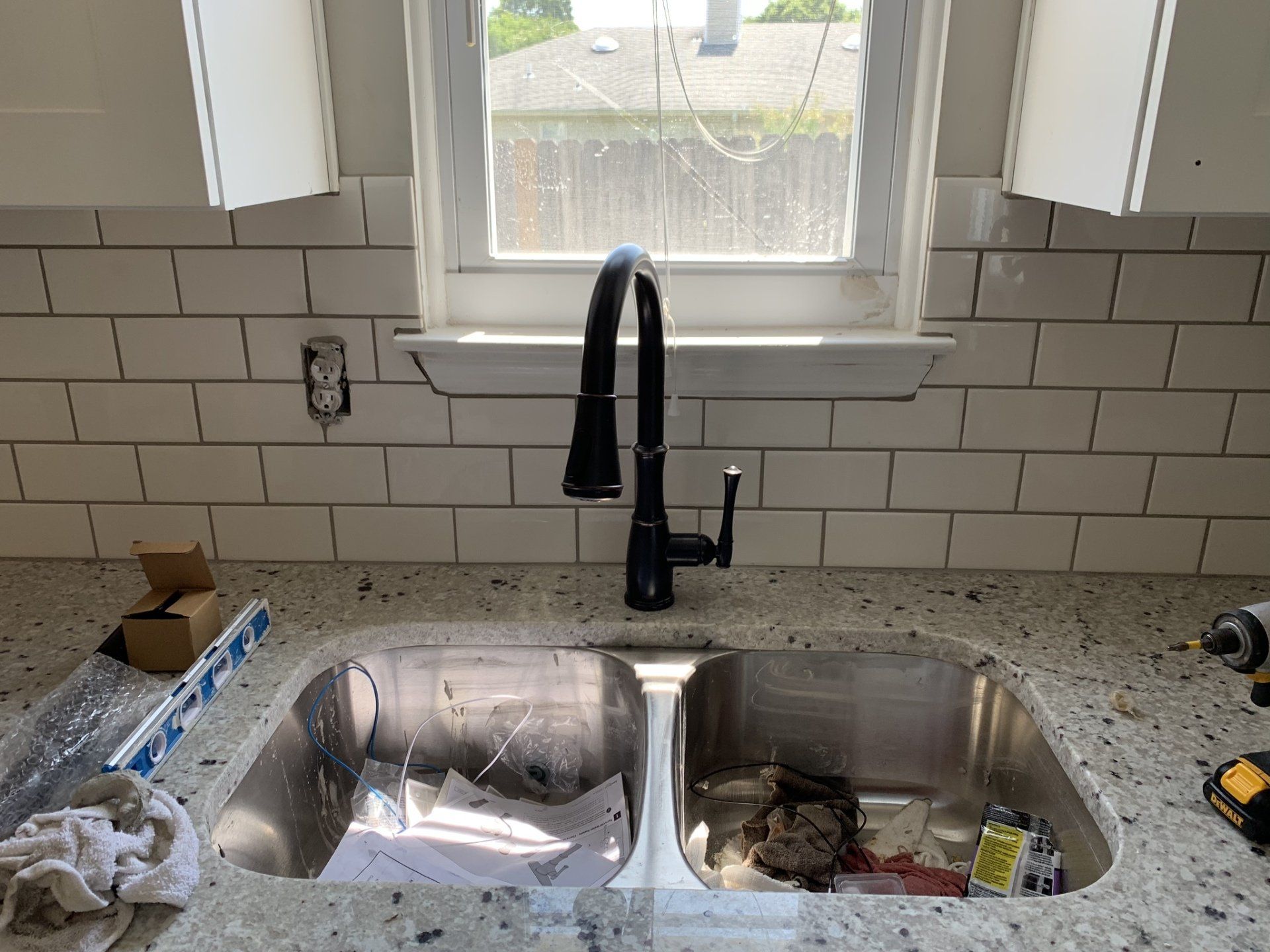 A kitchen sink with a black faucet and a window in the background.