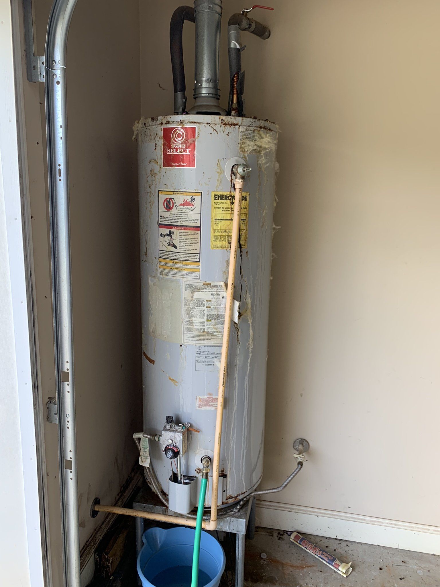 A water heater is sitting in a garage next to a door.