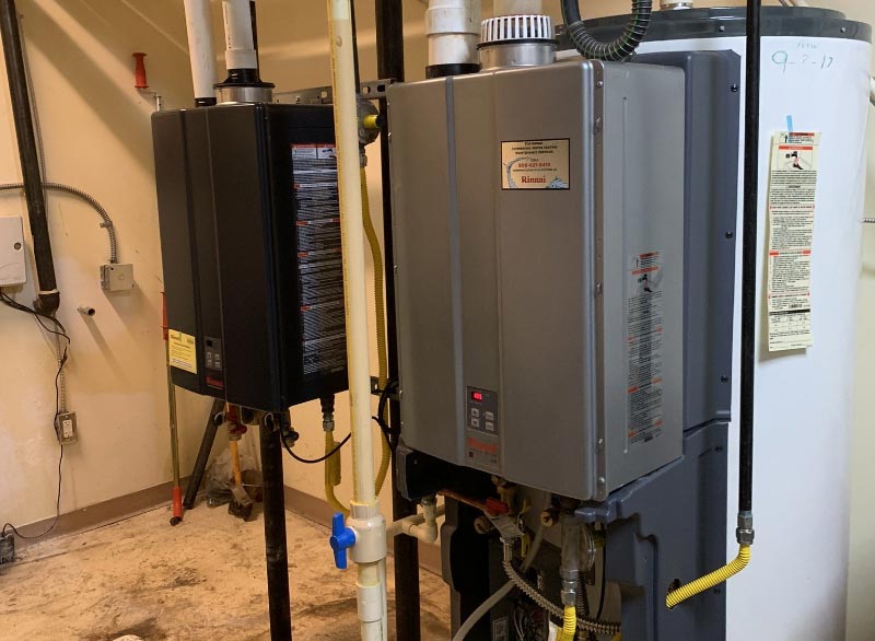 J Henry Plumbing installed tankless water heaters that are sitting next to each other in a room .