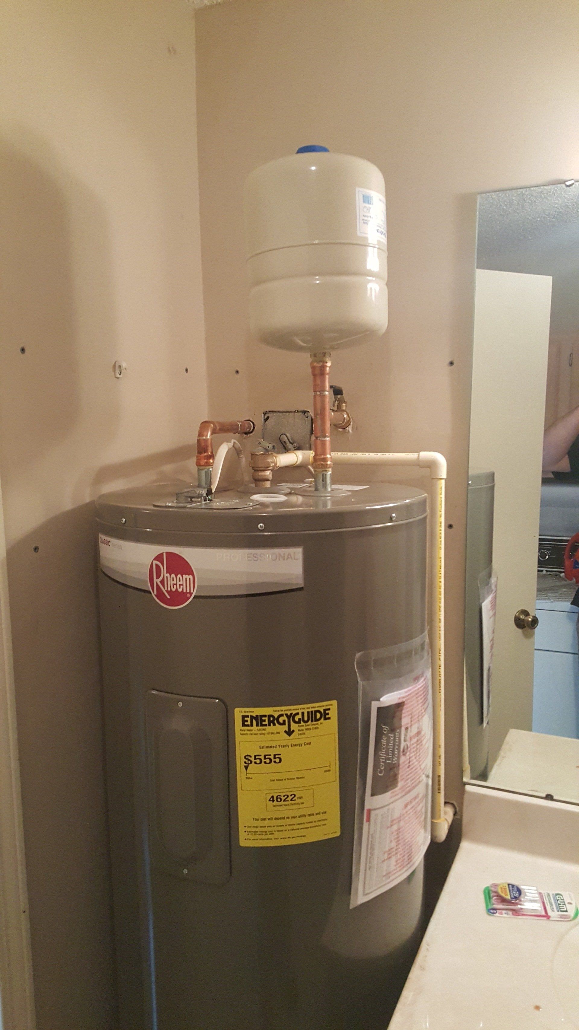 A water heater is sitting in a bathroom next to a sink.