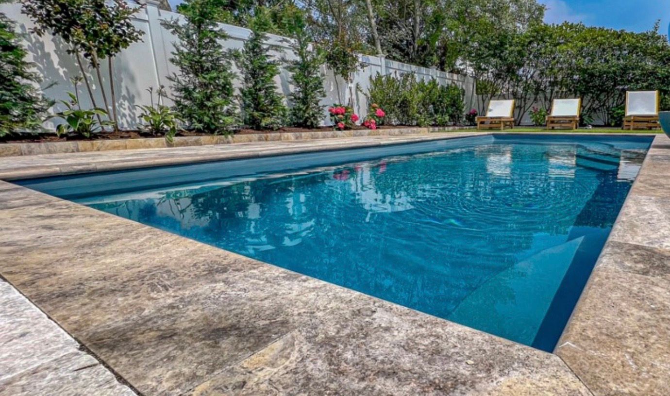 A large swimming pool surrounded by chairs and trees in a backyard.