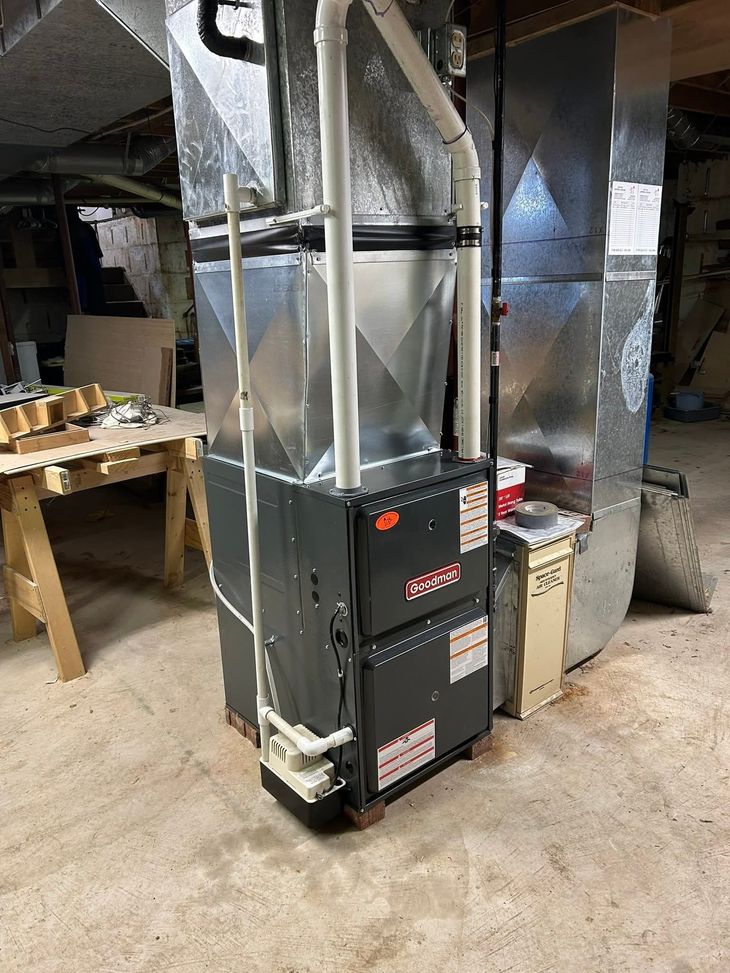 Basement HVAC furnace with silver ducts and black vents in a utility room