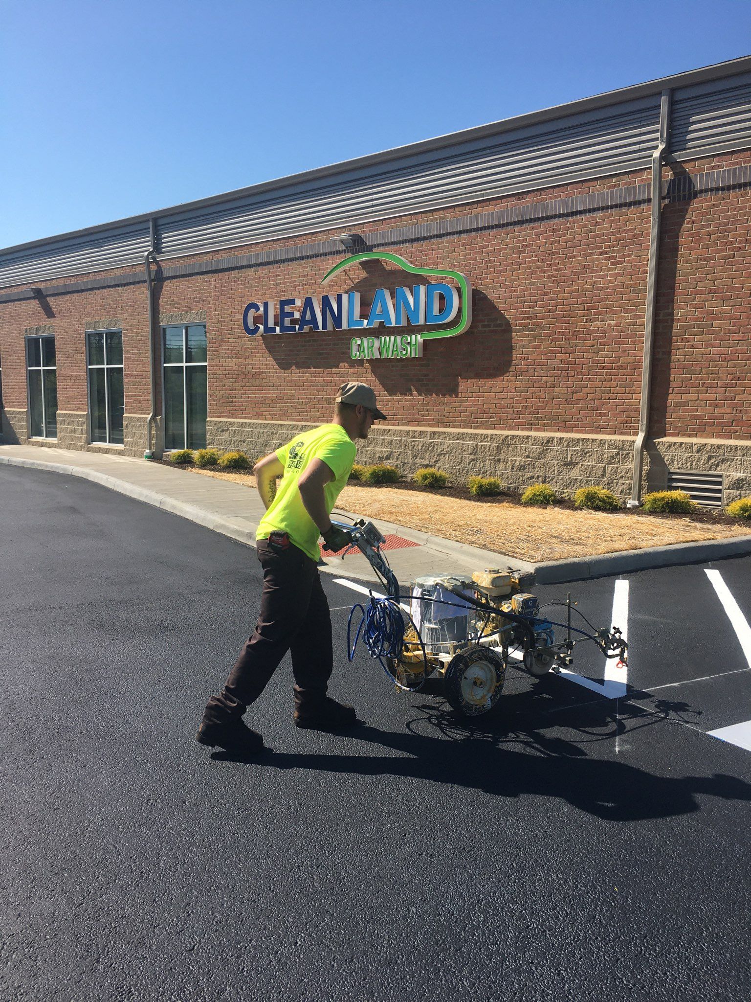 Man painting parking space lines with a machine at the Cleanland Center.