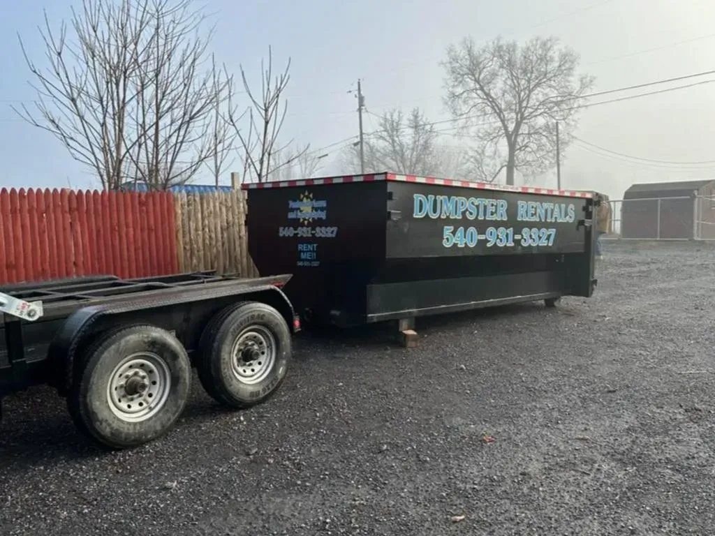 A dumpster is sitting on top of a trailer in a parking lot.