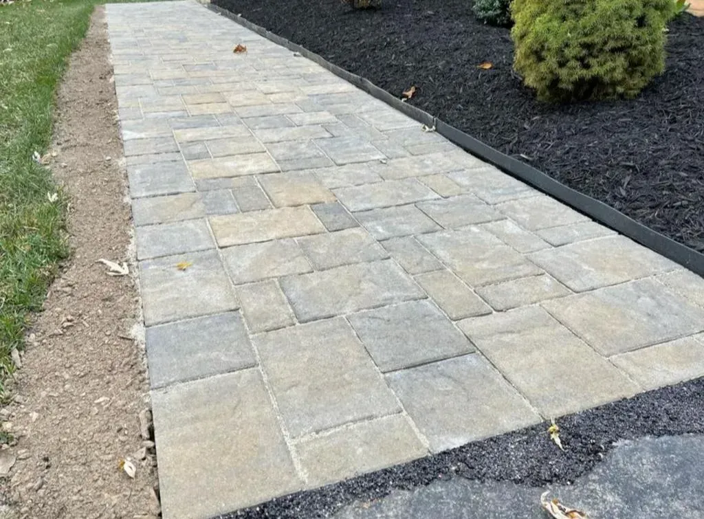 A stone walkway is being built next to a driveway.