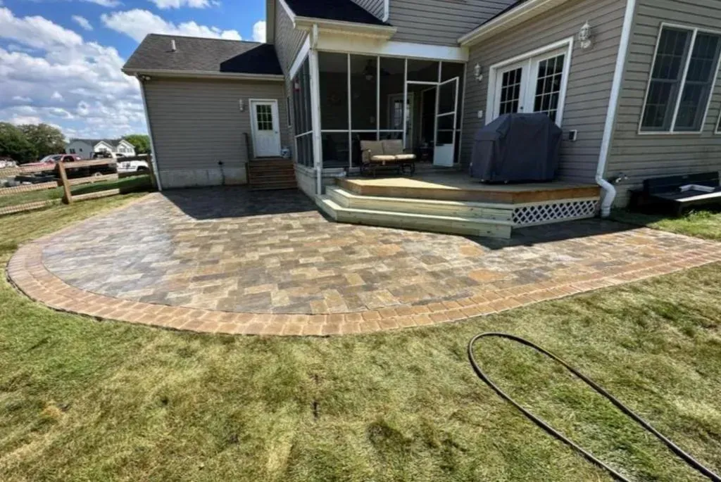 A house with a screened in porch and a patio in front of it.