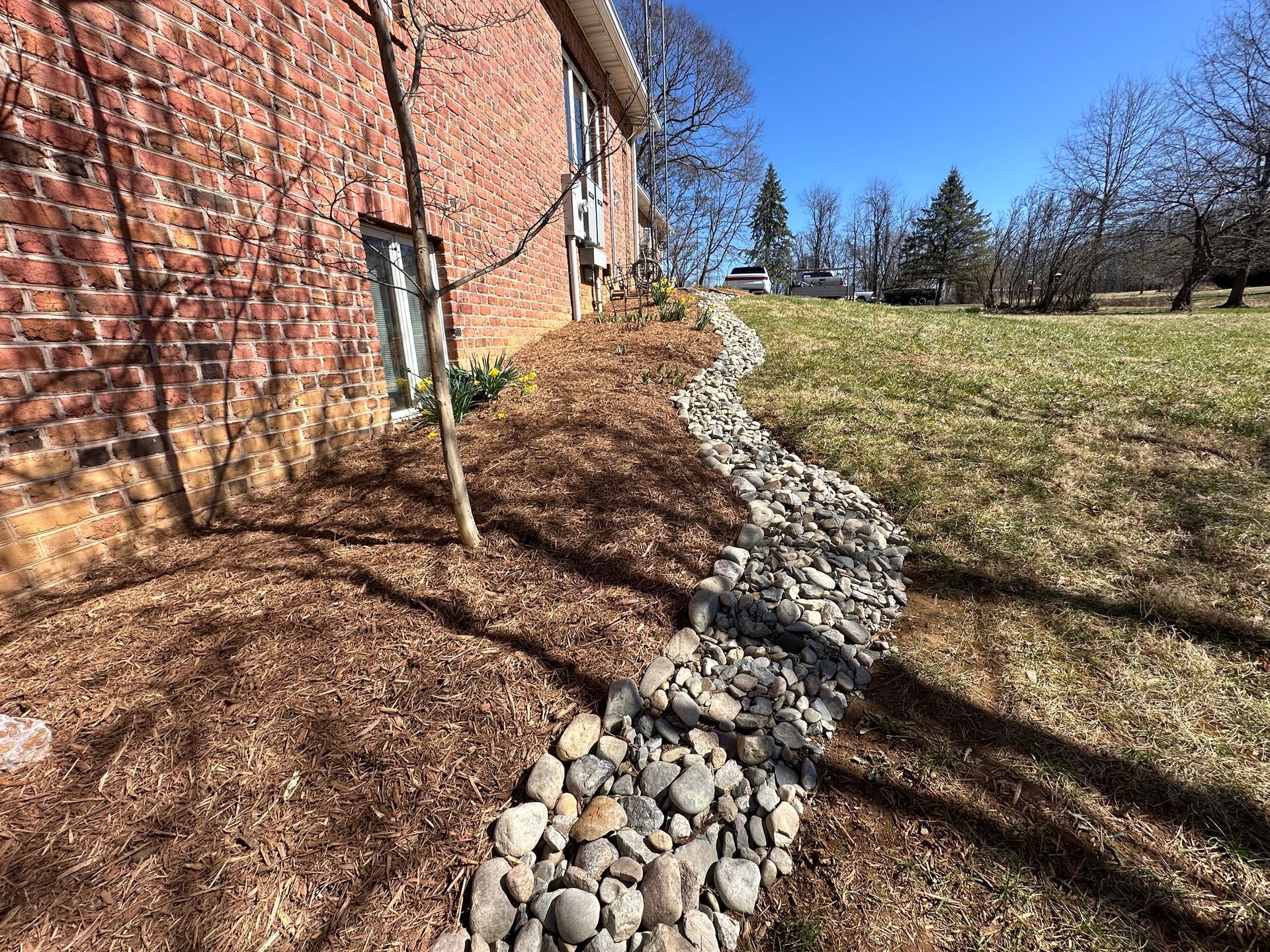 A drainage system is being installed on the side of a brick house.