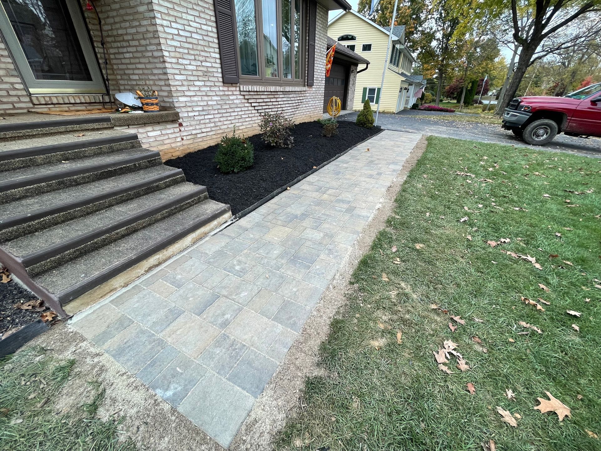 A sidewalk is being built in front of a brick house.