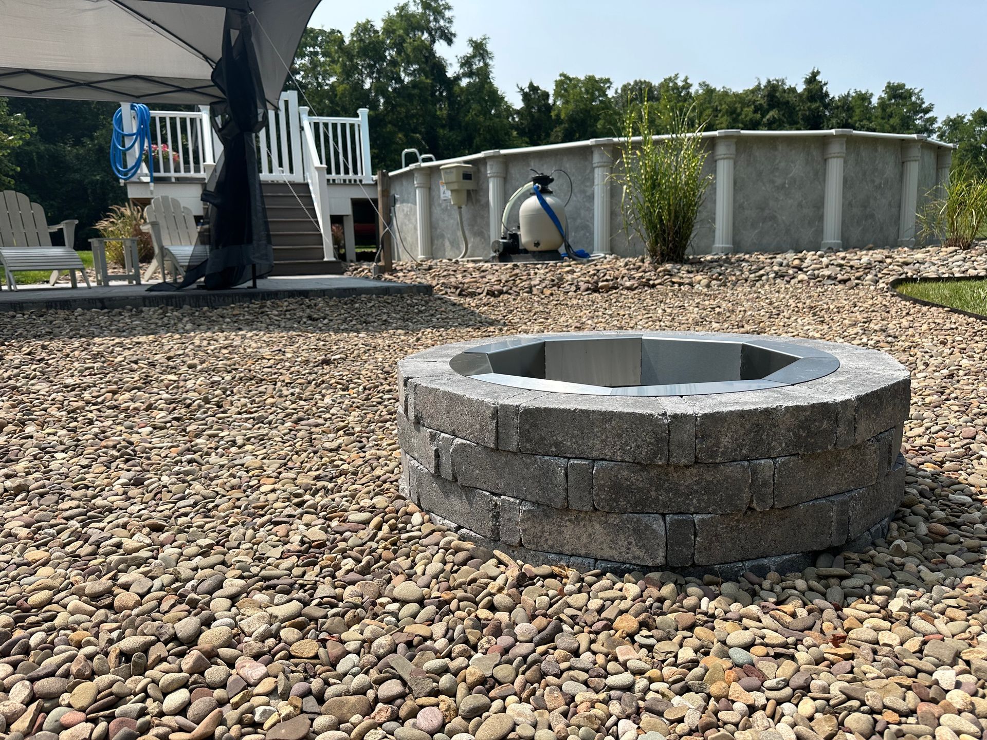 A fire pit is sitting on top of a pile of gravel next to a pool.
