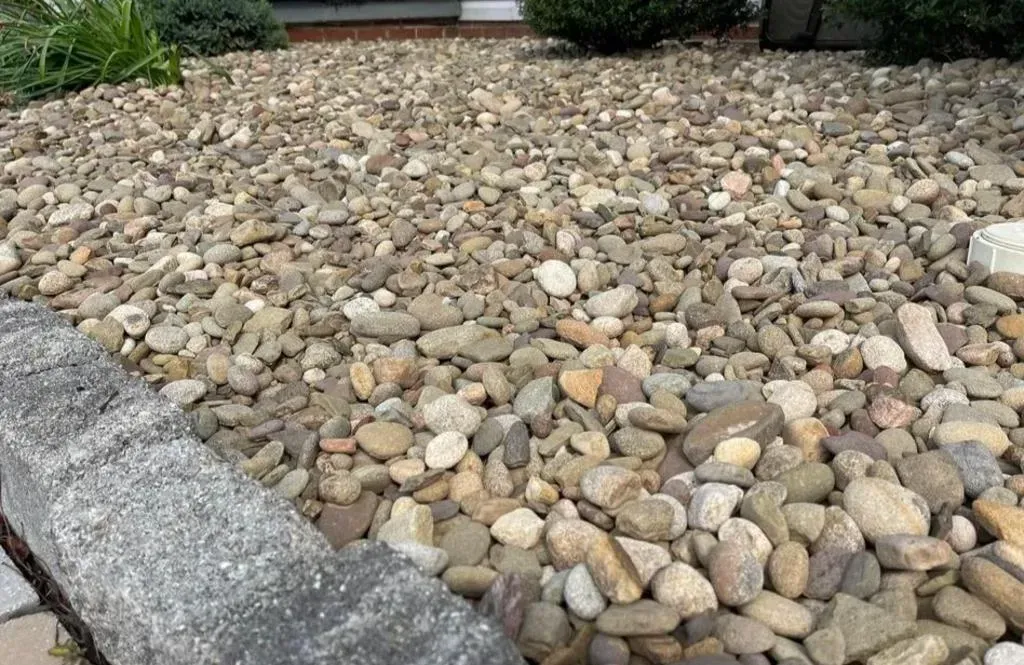 A pile of rocks in a yard next to a stone wall.